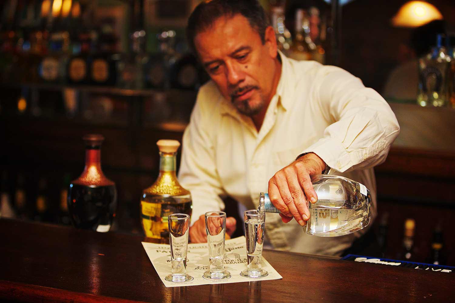 A bartender pouring a few drinks