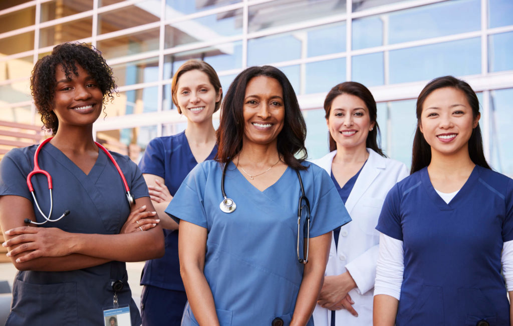 A group of smiling nurses standing outside of a hospital, part of a Minneapolis Website Development project.