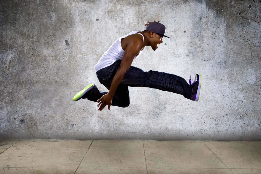 Black man dancing against a concrete wall. Learn more about our Twin Cities Web Design Agency