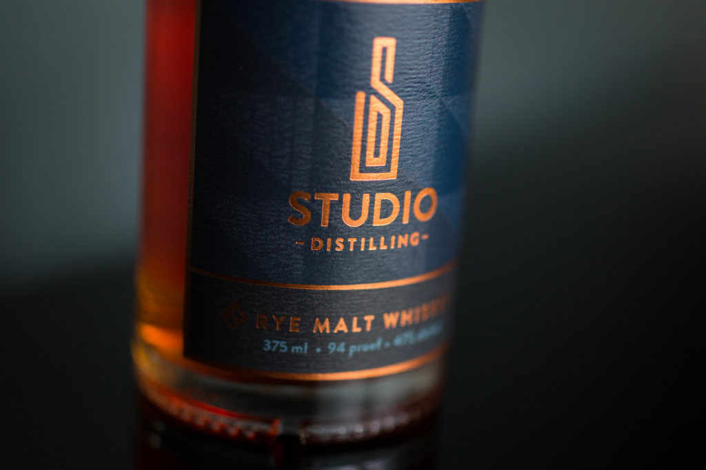 Custom logo design for Studio Distilling on bottle.