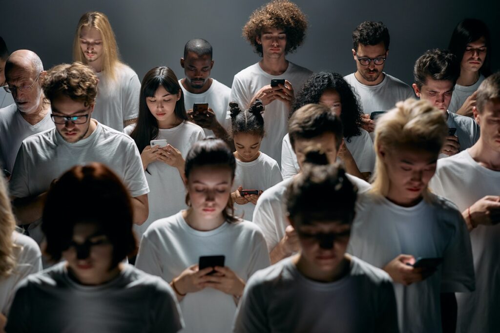 A group of phone users in white t-shirts assemble in a dimly lit room